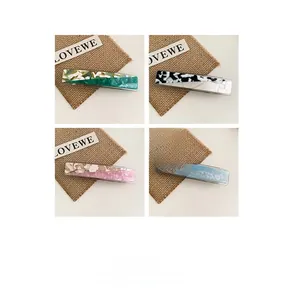 Detail showing acetate hair clips in four marble patterns with spring clip design