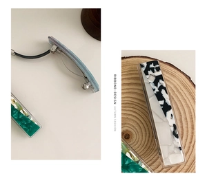 Detail of floral and marble texture hair clip on rustic wood with spring clip view