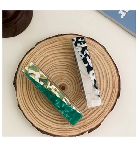 Macro shot of rectangular acetate hair clips with green marble and mosaic patterns
