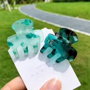 Macro view of light green floral and dark emerald green marble pattern hair claws