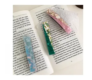 Detailed macro of three floral acetate rectangle hair clips on vintage paper and books
