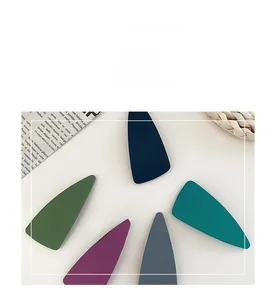 Detail shot of five matte triangle hair clips in navy blue, green, and purple shades