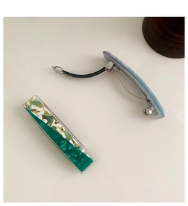 Detail of green floral and blue water ripple marble acetate hair clips with silver spring