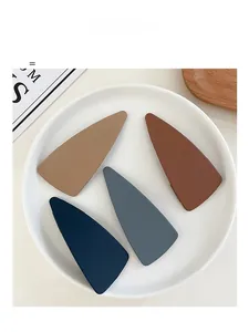 Detail of matte acrylic triangle hair clips in khaki, red, blue and gray colors
