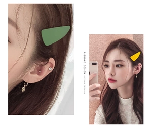 Detail of matte green and yellow triangular hair clips on model with aesthetic frosted finish