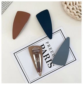 Close-up of four matte triangle hair clips in vintage navy, blue, and brown tones