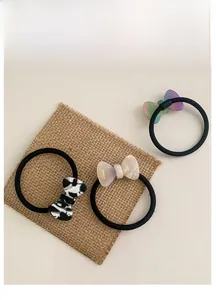 Detailed view of three elastic hair ties with marble-patterned acetate bow decorations