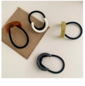 Detailed view of four acetate hair ties with C-shaped resin charms in diverse colors