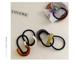 Detailed close-up of acetate bow hair ties and U-shaped clips in elegant marble textures
