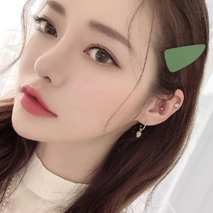 Matte green triangle hair clip in minimalist geometric design worn by a model