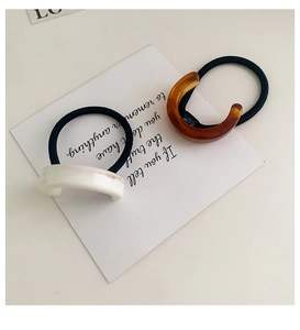 Detail of high-elasticity hair ties with white marble and amber resin C-shaped charms