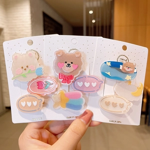 Close-up of glitter resin hair clips featuring bear and tulip designs on white cards