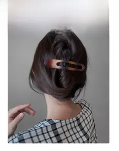 Gros plan d'une pince à cheveux en acrylique écaillé portée sur une demi-queue de cheval