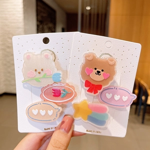 Close-up of glittery cartoon bear and tulip hair clips on a white display card