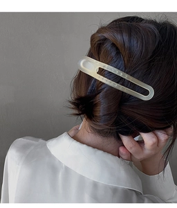 Barrette minimaliste en acrylique crème mat avec découpe ovale sur cheveux foncés élégants