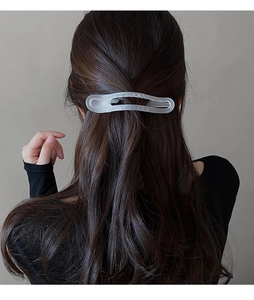 Détail d'une pince à cheveux en acrylique mat sur cheveux bruns pour un style élégant