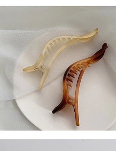 Détail de pinces à cheveux bananes mates beige et marron avec dents internes et ressort