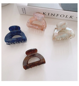 Close-up of tortoise shell and marble acetate hair claws on a minimalist white desk
