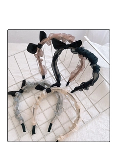 Detail of pleated fabric headbands with bow accents in various colors in a white basket