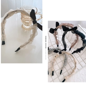 Detailed texture of pleated organza headband with delicate black ribbon bow accents