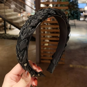 Detailed close-up of thick black woven headband with golden sparkles for women