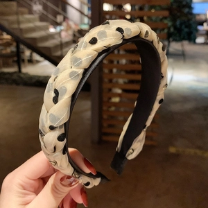Detail of twisted white polka dot chiffon fabric on a wide black headband with a subtle shimmer