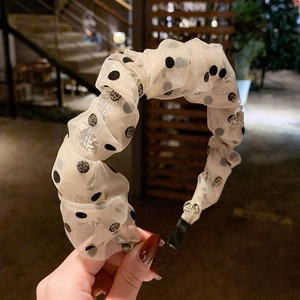 Detail of pleated beige organza headband with black polka dots and fine gold glitter