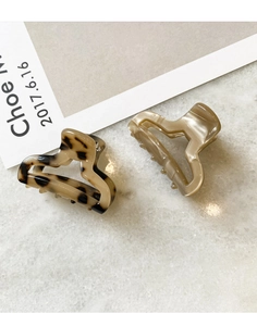 Close-up of tortoise shell and champagne resin hair clips on marble background