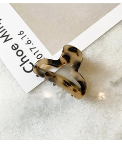 Close-up of a mini acetate heart hair claw clip with a vintage leopard tortoiseshell pattern