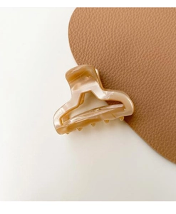 Close-up of small amber acetate hair claw clip with elegant marble pattern texture