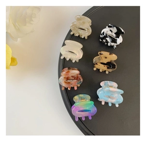 Macro detail of various mini acetate hair claw clips displayed on a black tray