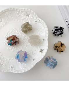 Macro shot of assorted acetate hair claws with marble and tortoise patterns on white plate