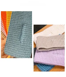 Dettaglio di fasce in lana lavorata a maglia multicolore con trama a coste e foro per coda di cavallo