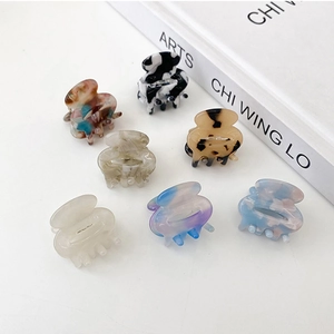Set of 7 mini acetate hair claws in tortoise shell and marble patterns on white table