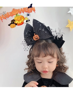 Detail of Halloween bow headband with silver spiders and orange pumpkin on a young child