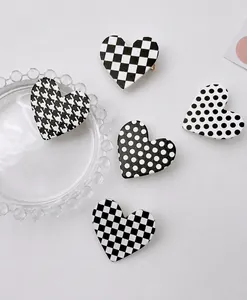 Detail of five heart-shaped hair clips featuring black and white checkerboard and polka dots