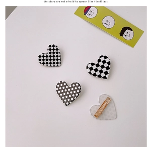 Detailed view of heart-shaped hair clips featuring checkered and polka dot acrylic patterns