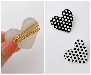 Detail view showing polished metal clip and checkered heart hairpins on white background