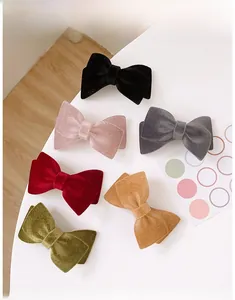 Flat lay of velvet bow hair clips in six elegant colors showing rich fabric texture
