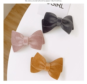 Three velvet bow hair clips in grey, pink, and yellow displayed on a white background