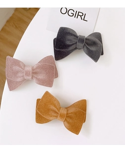 Detailed macro view showing three elegant flocked velvet bow hair clips in gray, pink, and yellow