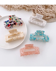 Flat lay of five acetate hair claws in floral and marble patterns for woman