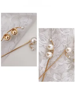 Detailansicht der goldenen Haarnadel mit eleganten weißen Perlen auf Spitzenhintergrund