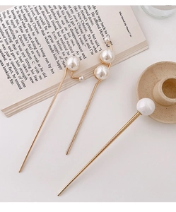 Detail von drei eleganten goldenen Haarnadeln mit Perlen auf Vintage-Buchseiten