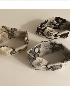 Close-up of three knitted headbands with cartoon bear patterns and twisted knot design