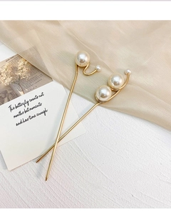 Detailansicht eleganter goldener Haarnadeln mit weißen Perlen auf dekorativem Stoffhintergrund
