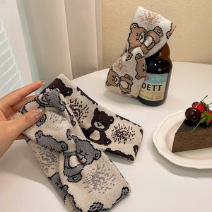 Cartoon bear knitted twist headband for women shown in soft cream and brown tones