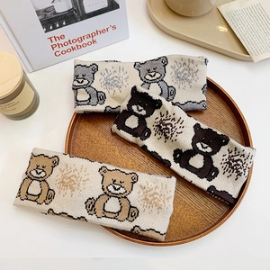 Three minimalist knitted headbands with cartoon bear patterns in grey and brown tones