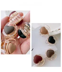 Macro view of heart-shaped acrylic hair clips with beaded gold edges in Morandi colors