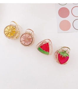 Dettaglio di quattro mini mollette per capelli con motivi di limone, arancia, anguria e fragola